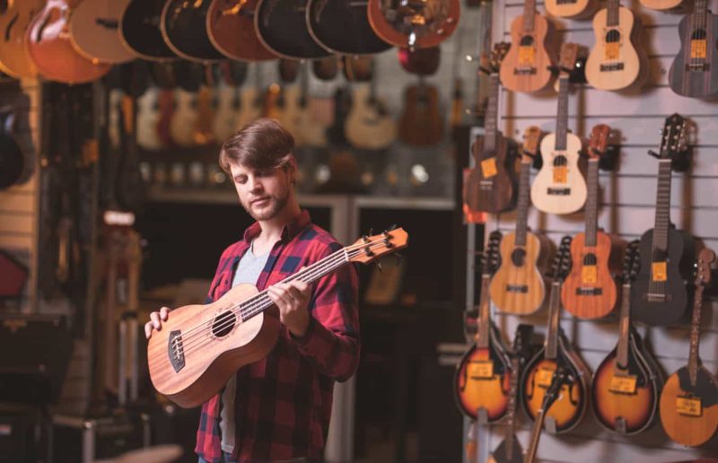 Junger Musiker mit Gitarre in einem Laden
